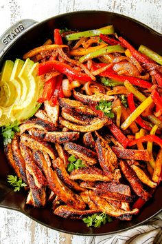 a skillet filled with chicken, peppers and avocado