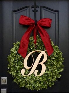 a black door with a red bow and monogrammed wreath