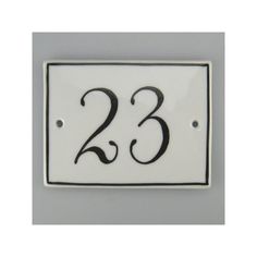 a white and black house number sign with the number 23 on it's side