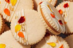 some cookies are decorated with white frosting and colorful leaves on them, as well as gold trimmings