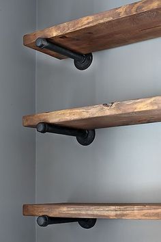 three wooden shelves with metal handles and knobs on each shelf, against a gray wall