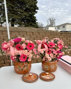 three vases filled with pink flowers sitting on top of a table next to a box