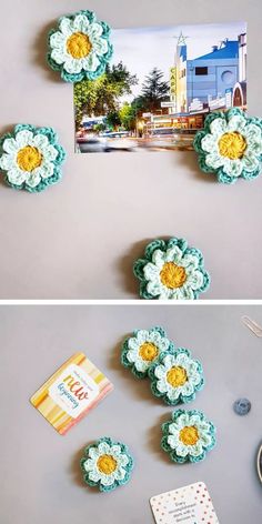 crocheted flowers are placed on the table next to a photo frame and magnets