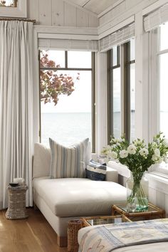 a living room filled with furniture and large windows overlooking the water in front of it