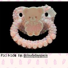 a pink teddy bear brooch with sequins on it's back and the words sweet in white letters