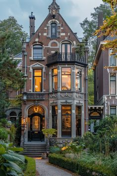 a large house with lots of windows and plants in the front yard, along with steps leading up to it