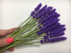 purple flowers are being held by a woman's hand