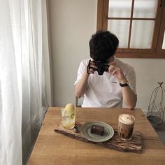 a man taking a photo of his food and drink on the table in front of him