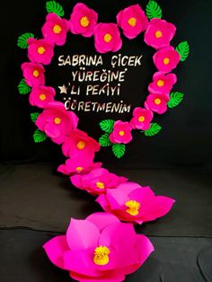 paper flowers are arranged in the shape of a heart with words written on it and two large pink flowers