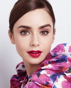 a woman with dark brown hair and red lipstick wearing a pink flower print scarf around her neck