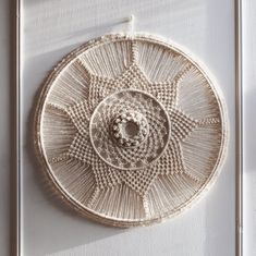 a woven object hanging on the side of a white door with sunlight coming through it