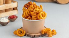 a cup filled with onion rings on top of a wooden stand next to other food items