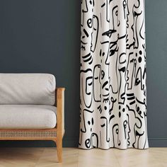 a white chair sitting in front of a curtain with black and white designs on it