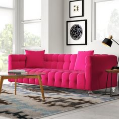 a living room with pink couches and pictures on the wall above it, along with a coffee table