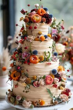 a three tiered cake with flowers on it is sitting on a table next to other desserts