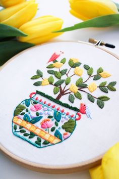 a cross stitch pattern with flowers and a vase on it, surrounded by yellow tulips