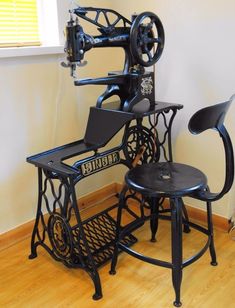 an old sewing machine sitting on top of a wooden floor next to a black chair