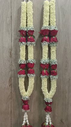 two red and white flowers are hanging on the wall next to each other with ribbons around them