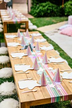 a long wooden table with paper hats on it's ends and place settings set up for an outdoor party