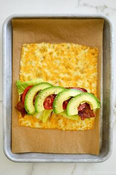 a square pizza with cheese, bacon and avocado on it in a pan