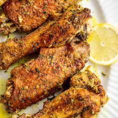 grilled chicken legs with lemon and herbs on a white plate, ready to be eaten