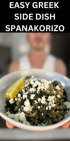 a person holding up a white bowl filled with spinach and feta cheese on top