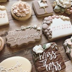 many decorated cookies on a wooden table with names and date written in white frosting