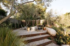 a garden with rocks, gravel and plants in the foreground is an outdoor seating area