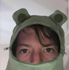 a person wearing a green frog hoodie over their face