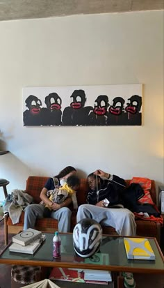 two people sitting on a couch in front of a wall with some pictures above them