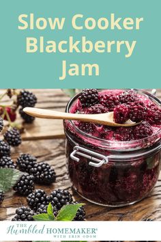 a jar filled with blackberry jam on top of a wooden table next to blackberries