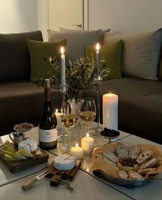 a table topped with wine glasses and plates filled with food next to candlelight candles