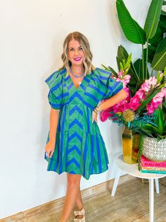 This playful mini dress combines blue and green in a charming chevron and stripe pattern, complete with a front panel and tiered ruffle seams. The ruffle sleeves and V-neckline add a touch of flirtiness, perfect for showing off your favorite necklaces. Whether you're heading to a weekend brunch or an outdoor concert, this dress has the perfect length for all heights. Style it with strappy sandals and a wide-brim hat for a chic, summery look! PRODUCT FIT - TRUE TO SIZE MODEL DETAILS - BRENNA IS A Green Ruffle Sleeve Mini Dress For Spring, Striped Ruffled Mini Dress For Vacation, Green Mini Dress With Ruffle Sleeves For Spring, Green Ruffle Sleeve Dress For Brunch, Green Tiered Ruffle Dress For Beach, Green Ruffle Sleeve Dress For Beach, Green Mini Dress With Ruffle Hem And Sleeves, Chic Green Mini Dress With Ruffle Sleeves, Striped Mini Dress With Ruffles And Short Sleeves