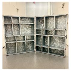 an open book case sitting on top of a cement floor in front of a white wall