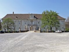 a large white building with cars parked in front of it and trees on the other side