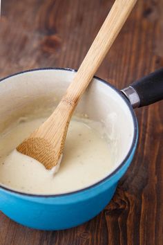 a wooden spoon in a blue pan filled with liquid on top of a wooden table