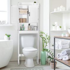 a white toilet sitting in a bathroom next to a bathtub filled with lots of towels