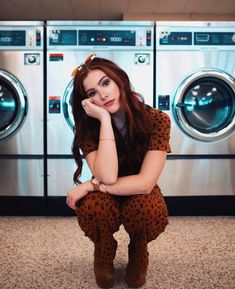 a woman sitting on the floor in front of a washer and dryer machine