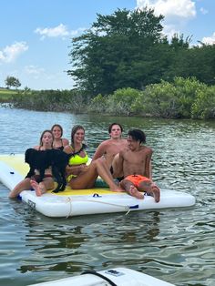 a group of people are floating in the water with a dog on a float board