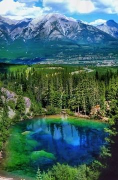 a lake surrounded by trees and mountains in the background