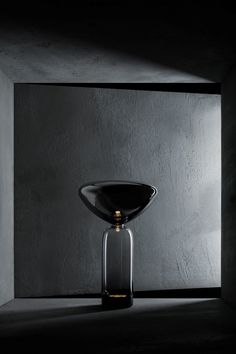 a black and white photo of a glass bowl on a table in a dark room