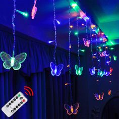 some lights that are hanging from the ceiling with remote controls in front of them and butterflies on the ceiling