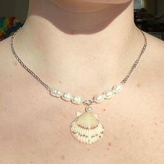 a woman wearing a necklace with a shell on it