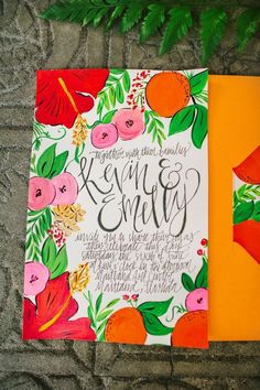 an orange and white wedding card with flowers