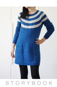 a woman standing in front of a white wall wearing a blue sweater and black tights