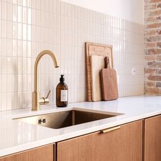 a kitchen sink with a wooden cutting board next to it and a soap dispenser on the counter