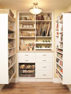 an organized pantry with white cabinets and drawers