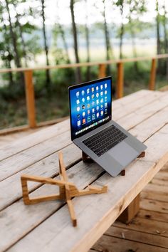 an open laptop computer sitting on top of a wooden table next to a picnic table