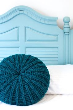 a blue headboard with a round knitted pillow on it