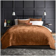 a bed with brown bedspread and pillows in a room that has black paneled walls